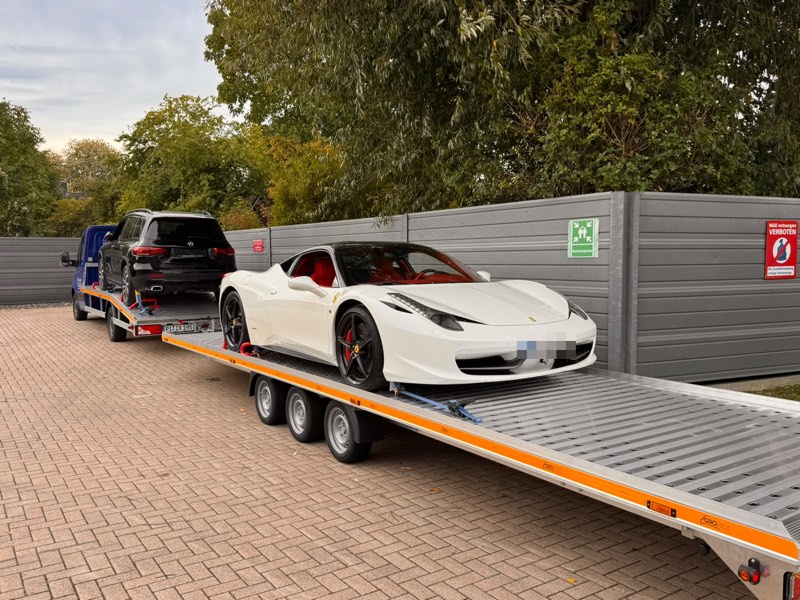 Weißer Sportwagen auf dem Anhänger, davor ein SUV auf dem Transporter