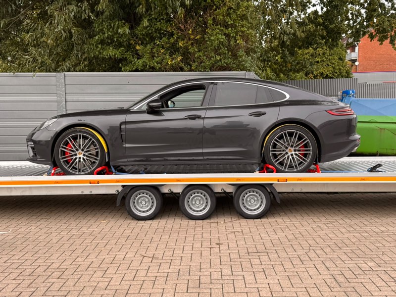 Dunkelgraue Limousine in der Seitenansicht auf dem dreiachsigen Anhänger