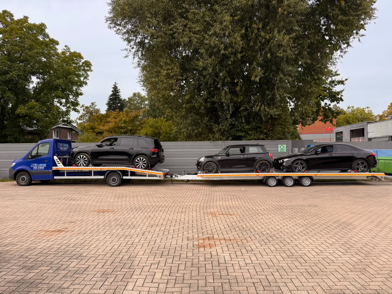 Blauer KTA-Nord-Transporter mit Anhänger, beladen mit mehreren Pkw